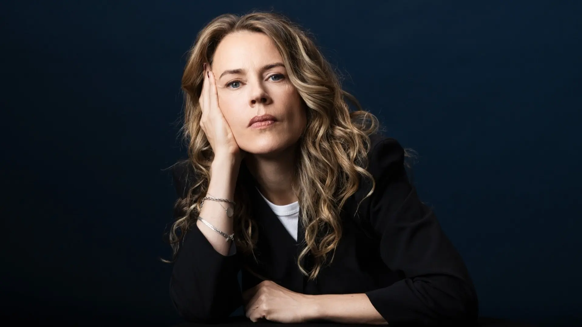 Porträttbild på låtskrivaren och författaren Annika Norlin som tittar in i kameran och låtar huvudet i höger hand.