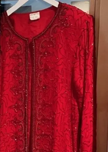 Frida Landbecker står framför en klädställning med festliga plagg, inklusive en röd och en svart klänning. Hon håller i flera accessoarer och inspirerar till hållbara val för julens outfits.