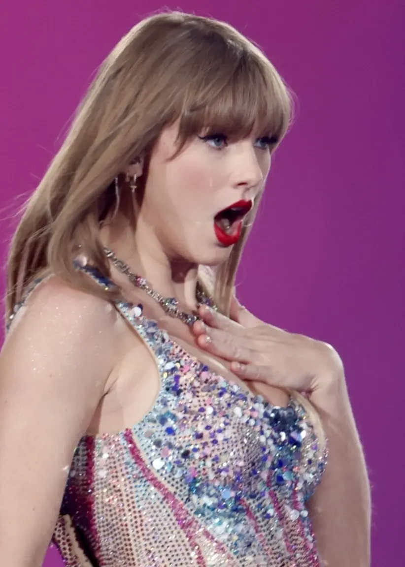 Taylor Swift uppträder på Friends Arena i Stockholm under sin turné ”The Eras Tour”. Hon bär en glittrande klänning och håller en mikrofon mot en bakgrund av starkt rosa ljus.