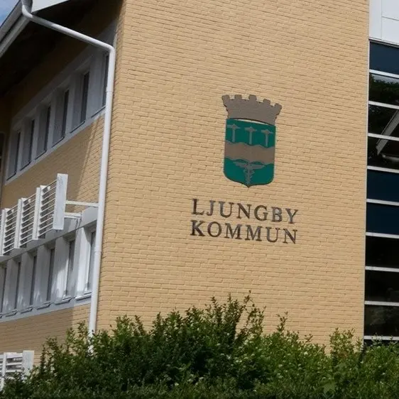 Silhuetter av tre personer framför en suddig bakgrund med träd och en byggnad. De kopplas till en nyhet om att anställda på Ljungby kommun fått sluta efter vanvård på en förskola.