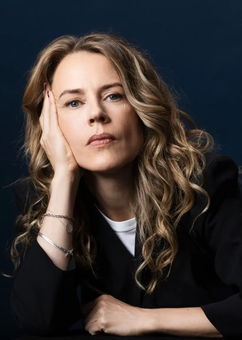 Porträttbild på låtskrivaren och författaren Annika Norlin som tittar in i kameran och låtar huvudet i höger hand.