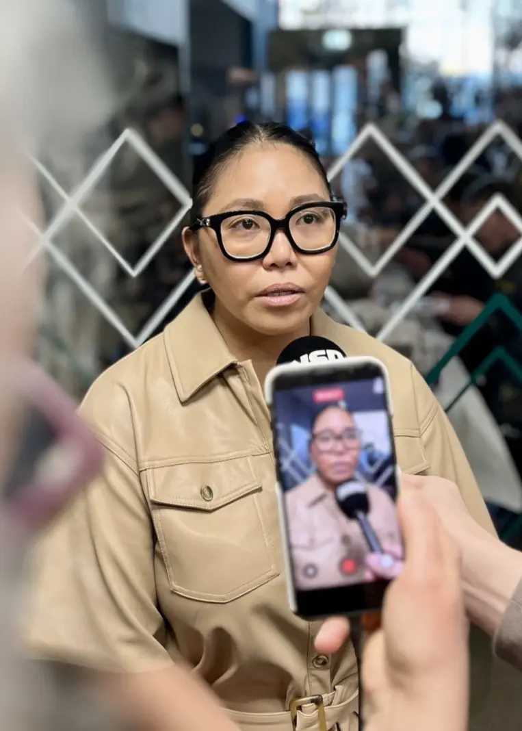 Salve Francisco, hyllad av räddningstjänsten i Luleå, ses i en ljus skjorta medan en person fotograferar henne med en mobiltelefon. Bakgrunden visar en offentlig plats med glasdetaljer.