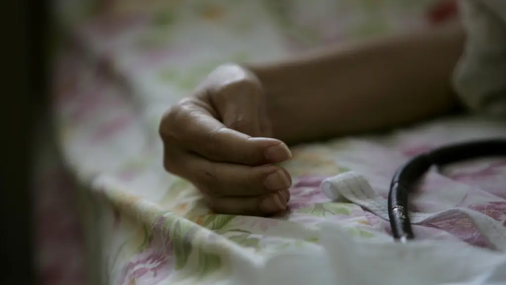 En bild i två delar. Vänster sida visar en person i vit tröja som sitter vid ett bord med papper spridda framför sig i ett kök. Höger sida visar en närbild av en fot på en person som ligger i en säng.