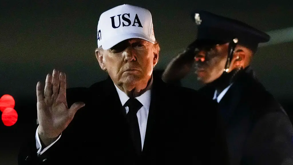 Donald Trump har vit keps och hälsar.