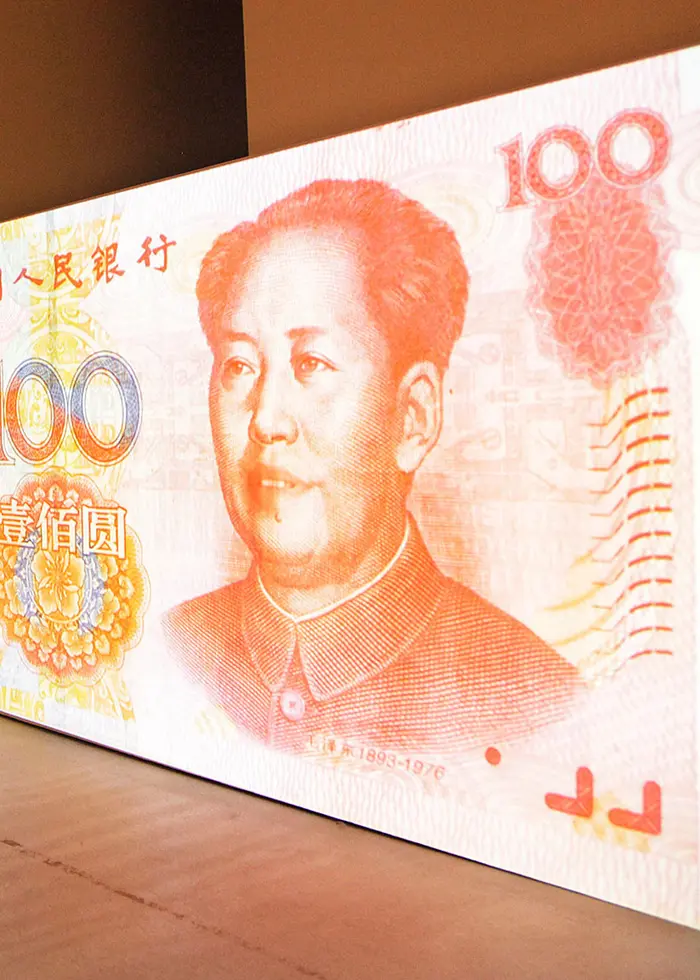 Två personer står och tittar på en kinesisk yuansedel.