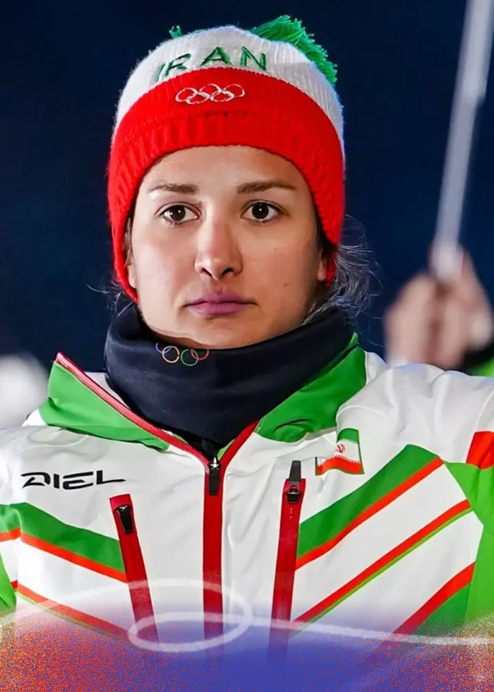 Irans fanbärare deltar i idrottarnas parad under invigningsceremonin för vinter-OS 2026 i Predazzo, Italien. De bär gröna och vita dräkter med nationella färger och håller Irans flagga.