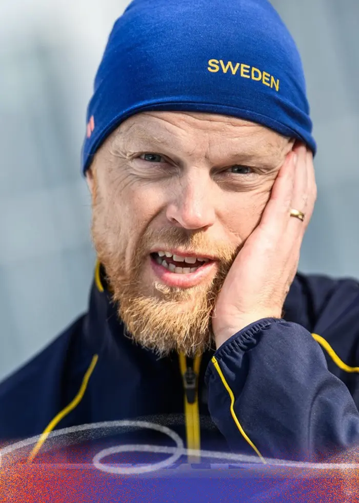 Två bilder visar en svensk idrottare i tävlingskläder och mössa med texten 'Sweden'. I bakgrunden syns snöklädda berg och en vinteridrottsarena med tydliga olympiska symboler.