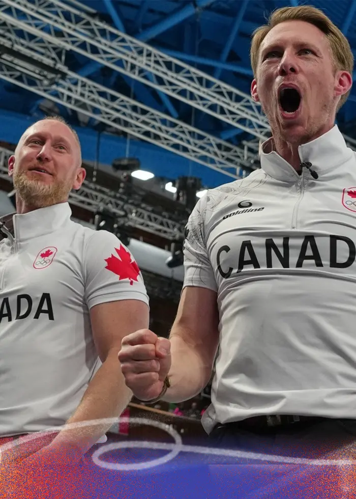 Två curlingutövare från det kanadensiska laget, klädda i vita tröjor med texten 'Canada' och röda lönnlöv, står på isen i en curlingarena. Till vänster syns en svensk spelare i mörk tröja.