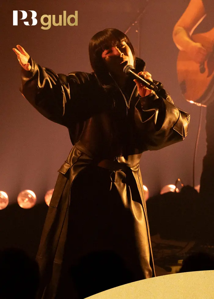 Artisten Yukimi, iklädd en mörk kappa på scen.