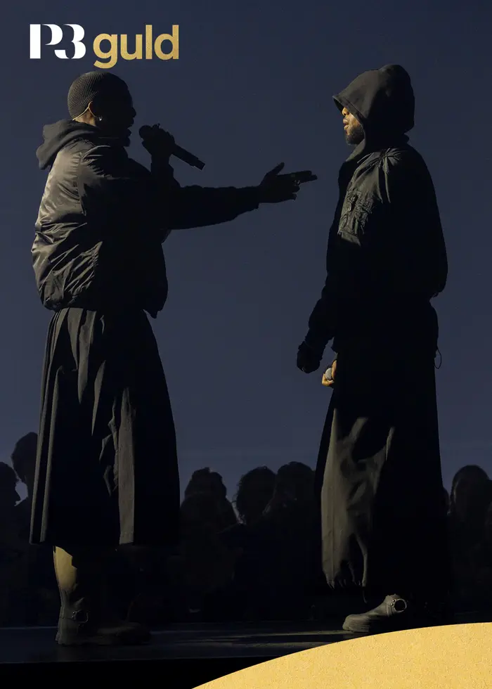 Två mörkklädda personer på en scen