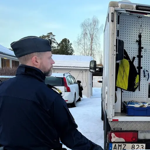 Poliser och kriminaltekniker undersöker ett fordon med öppna dörrar på en vintrig plats. Bredvid visas föremål, bland annat en sax och ett kort, på ett blommigt underlag, markerade som bevis.