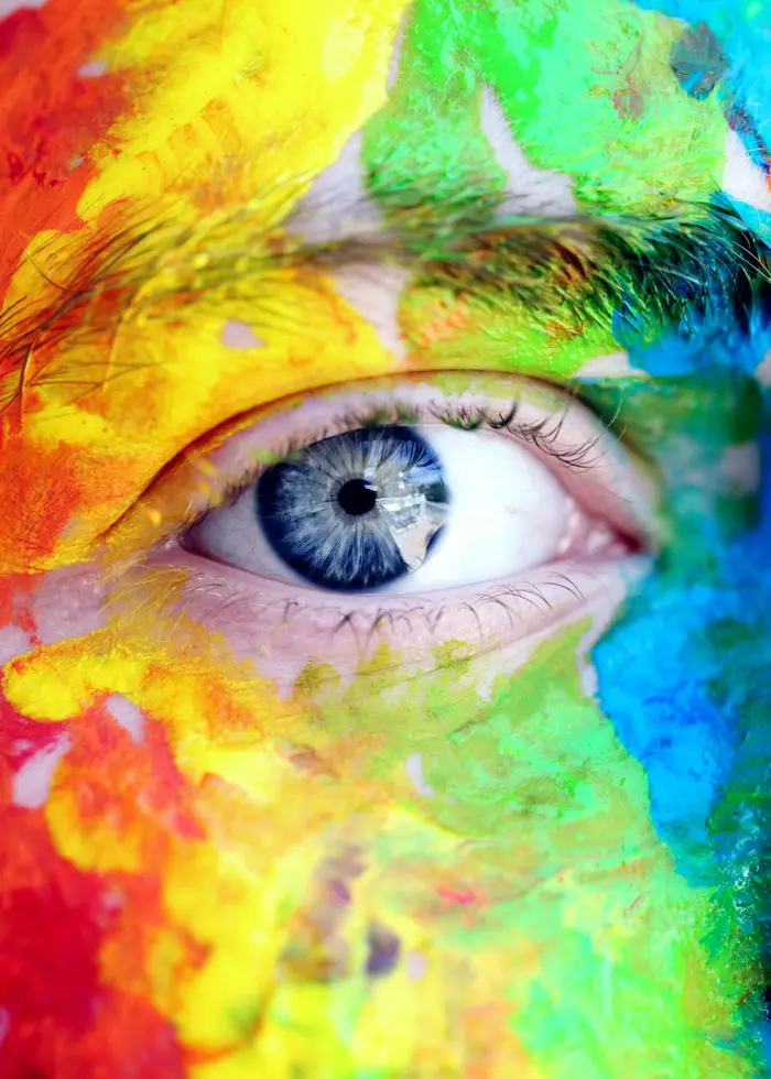 Närbild på en persons öga. Ansiktet målat i färgglada färger.
