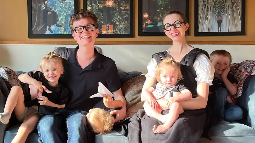 Två vuxna sitter i en soffa omgivna av barn.