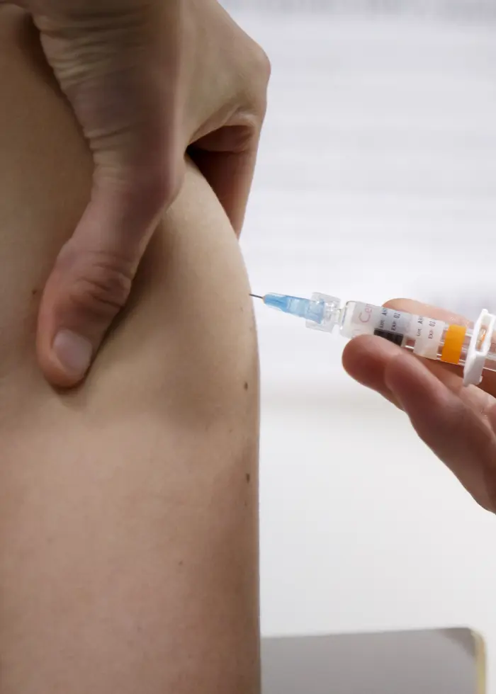 Kvinna får spruta i överarmen.