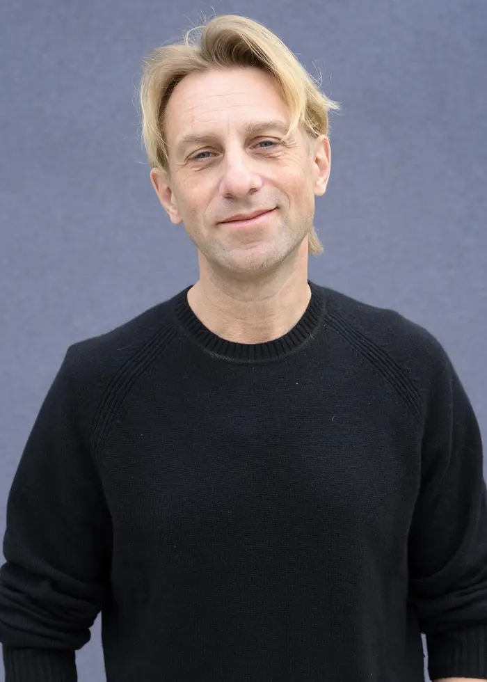 En leende man mot en blå bakgrund.