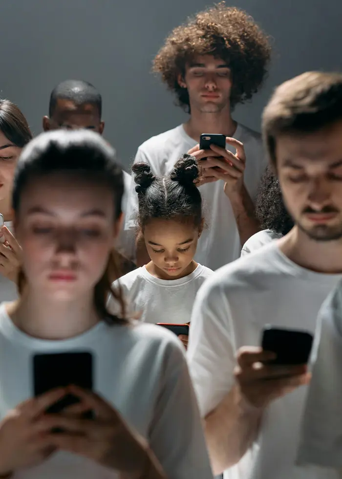 En grupp personer står och tittar ner i sina telefoner.