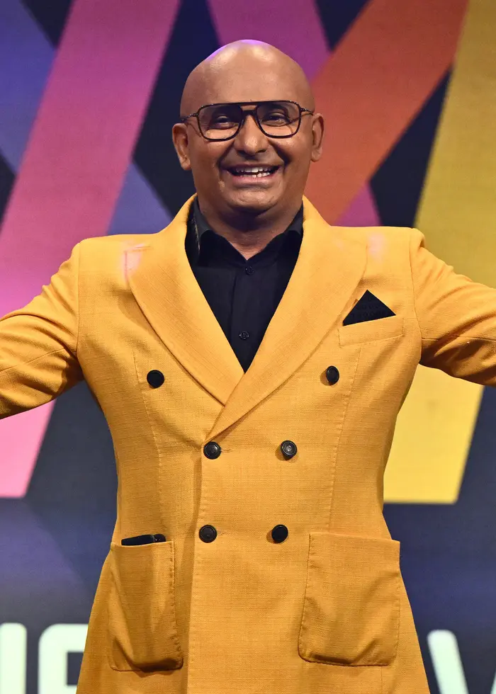 Man i gul kostym framför Melodifestivalloggan.