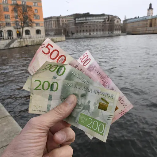 200- och 500-sedlar framför riksdagshuset och Rosenbad i Stockholm.