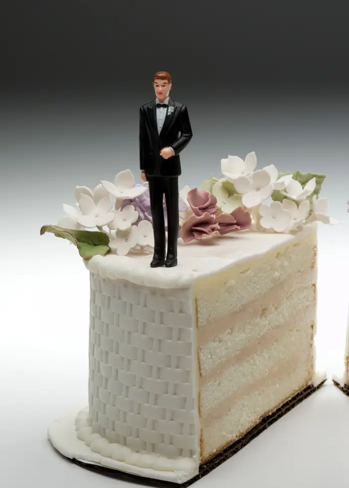Delad bröllopstårta med figurer på toppen.