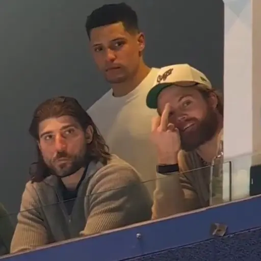 En ishockeyspelare i Toronto Maple Leafs blå uniform, nummer 88 William Nylander, skrinnar med pucken på isen under en match mot Vancouver Canucks. Bakgrunden visar publik och reklamskyltar.