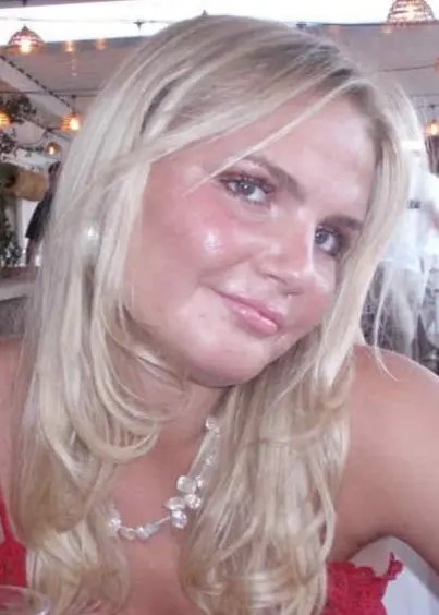 en blond ung tjej sitter på en restaurang iklädd ett rött linne, tittar in i kameran