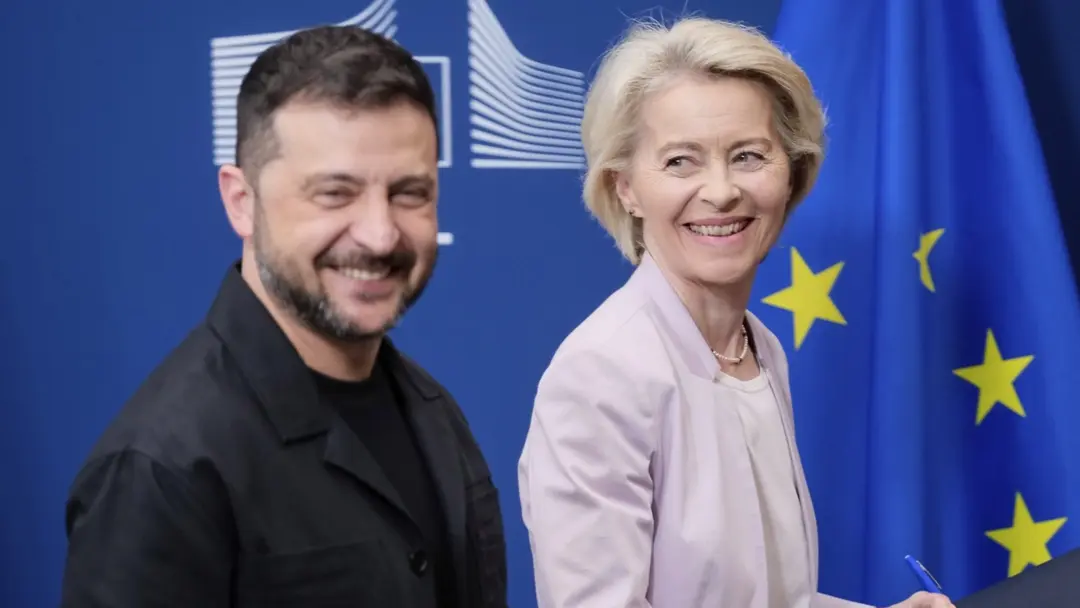 Ukrainas president Volodymyr Zelenskyj och EU-kommissionens ordförande Ursula von der Leyen ses vid EU:s högkvarter i Bryssel framför EU-flaggor, symboliserande samarbete mellan Ukraina och EU.