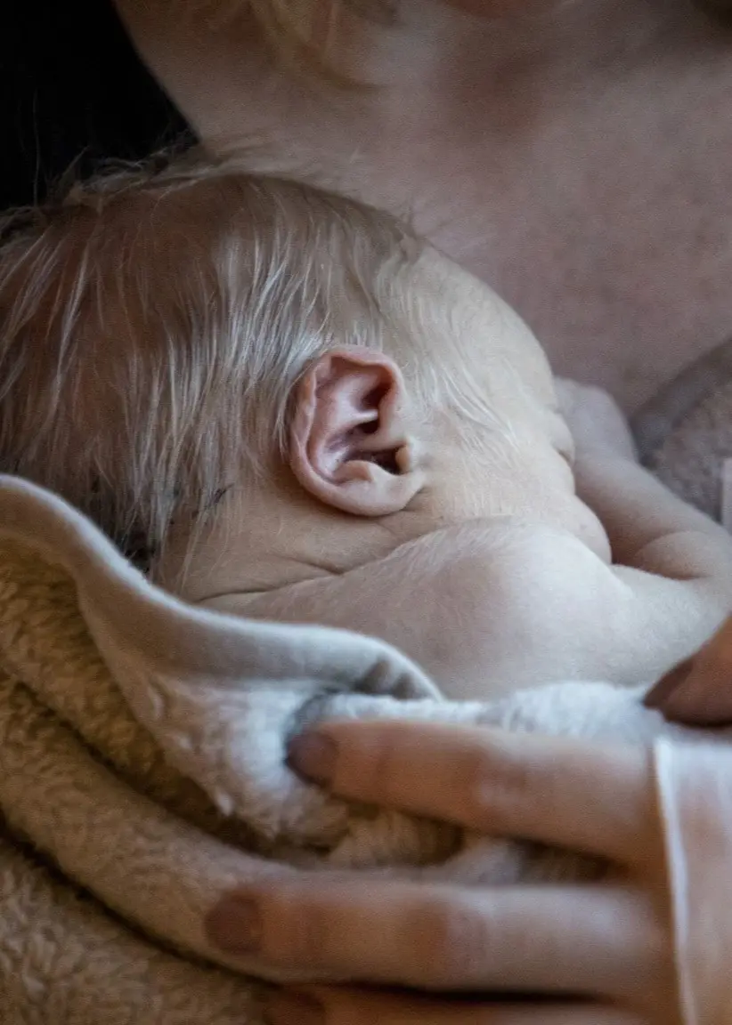 Ett nyfött barn blir omhållen av en vuxen. 