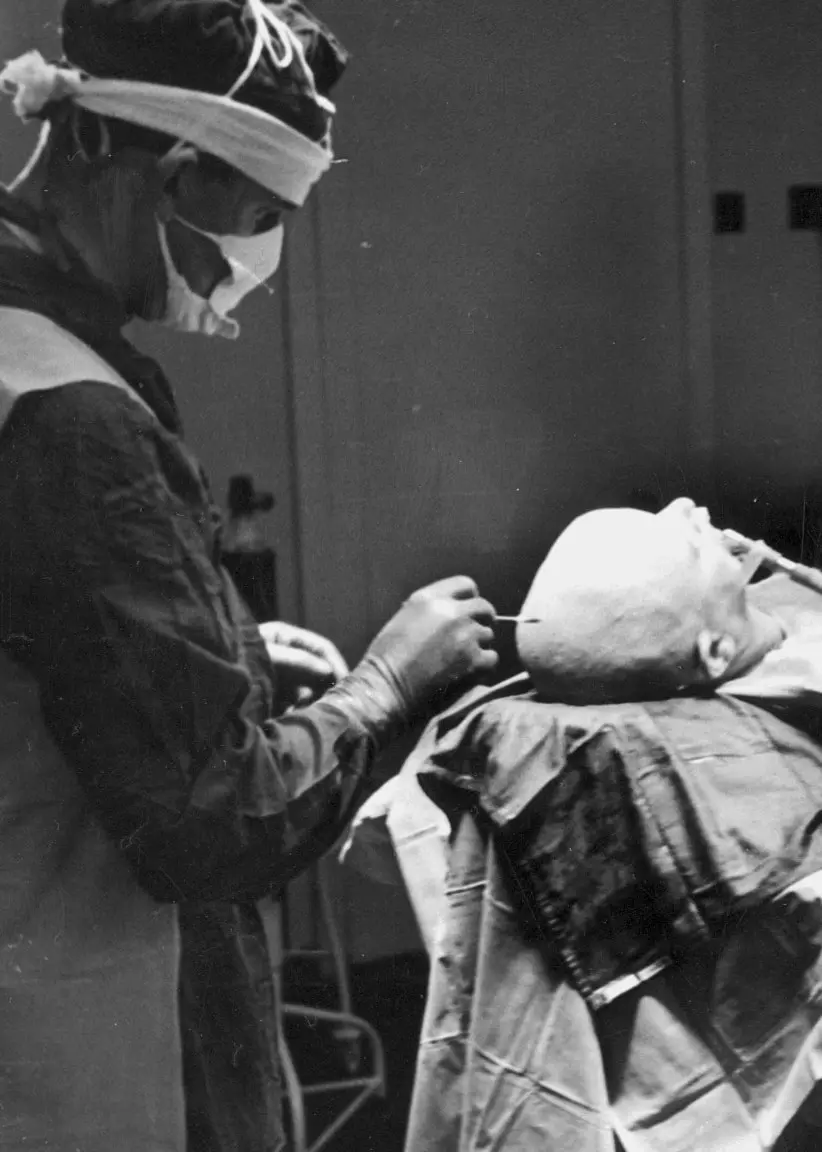 En patient ligger på en brits, med tre läkare runt om. Patienten får en lobotmi. 