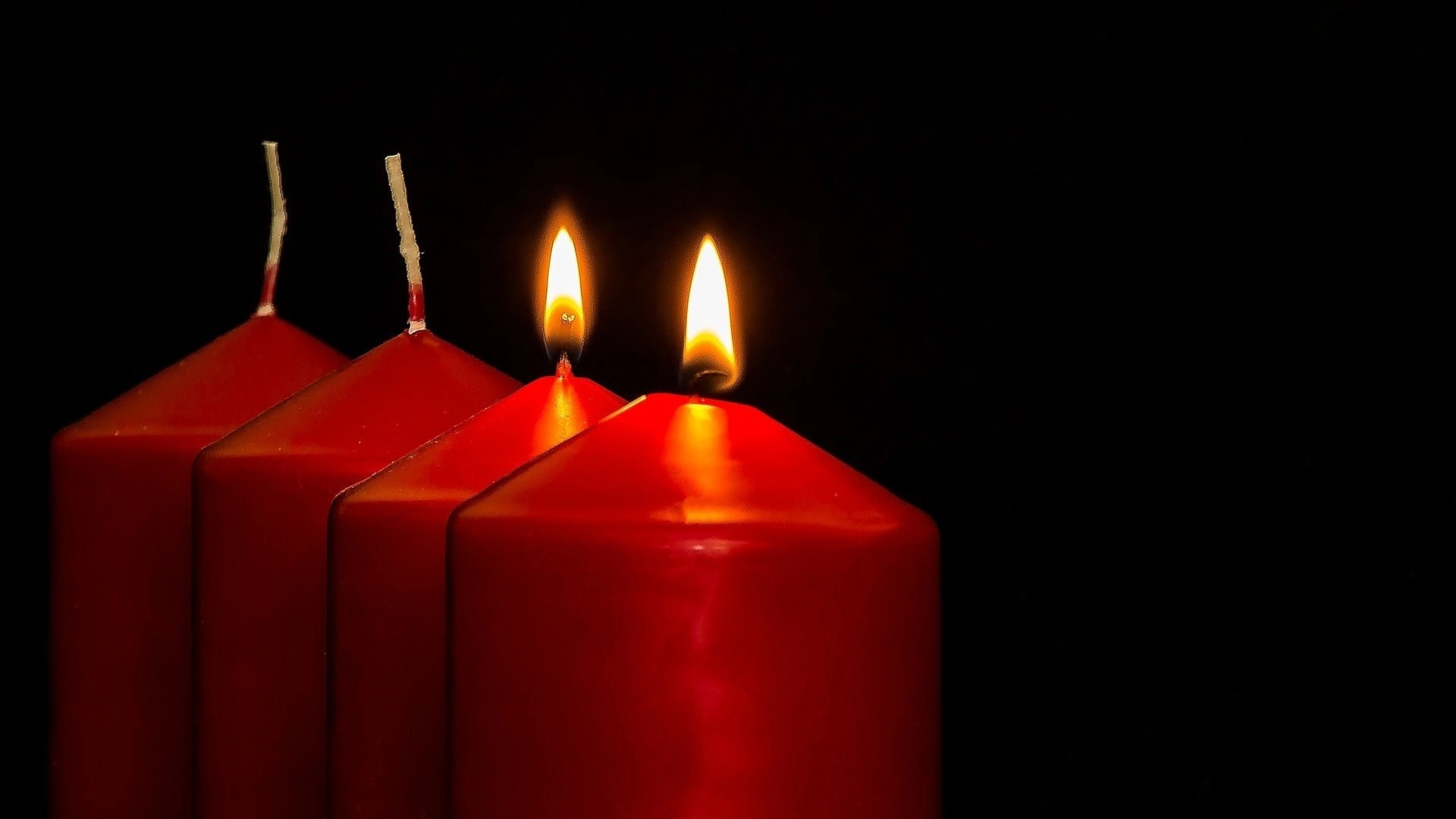 Två tända ljus i en adventsljusstake.
