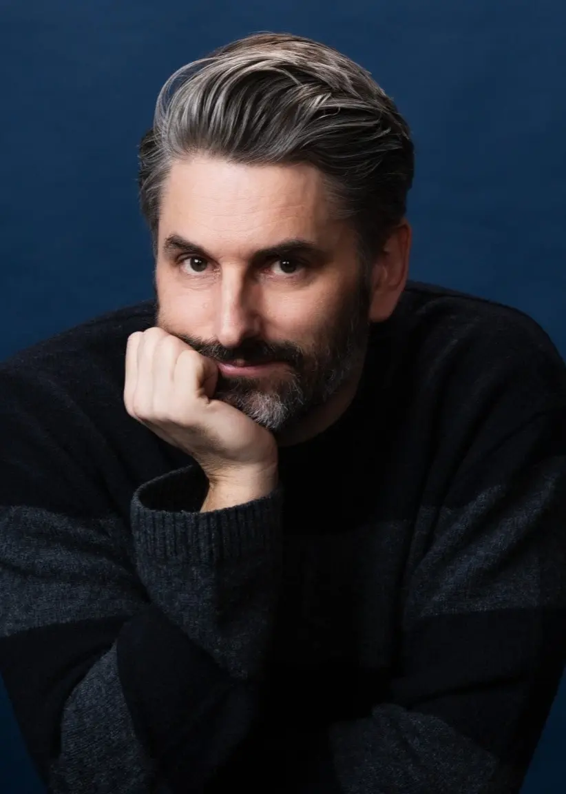 Portättfoto på förfataren Andrev Walden som lutar huvudetmöt höger hand och tittar in i kameran. 