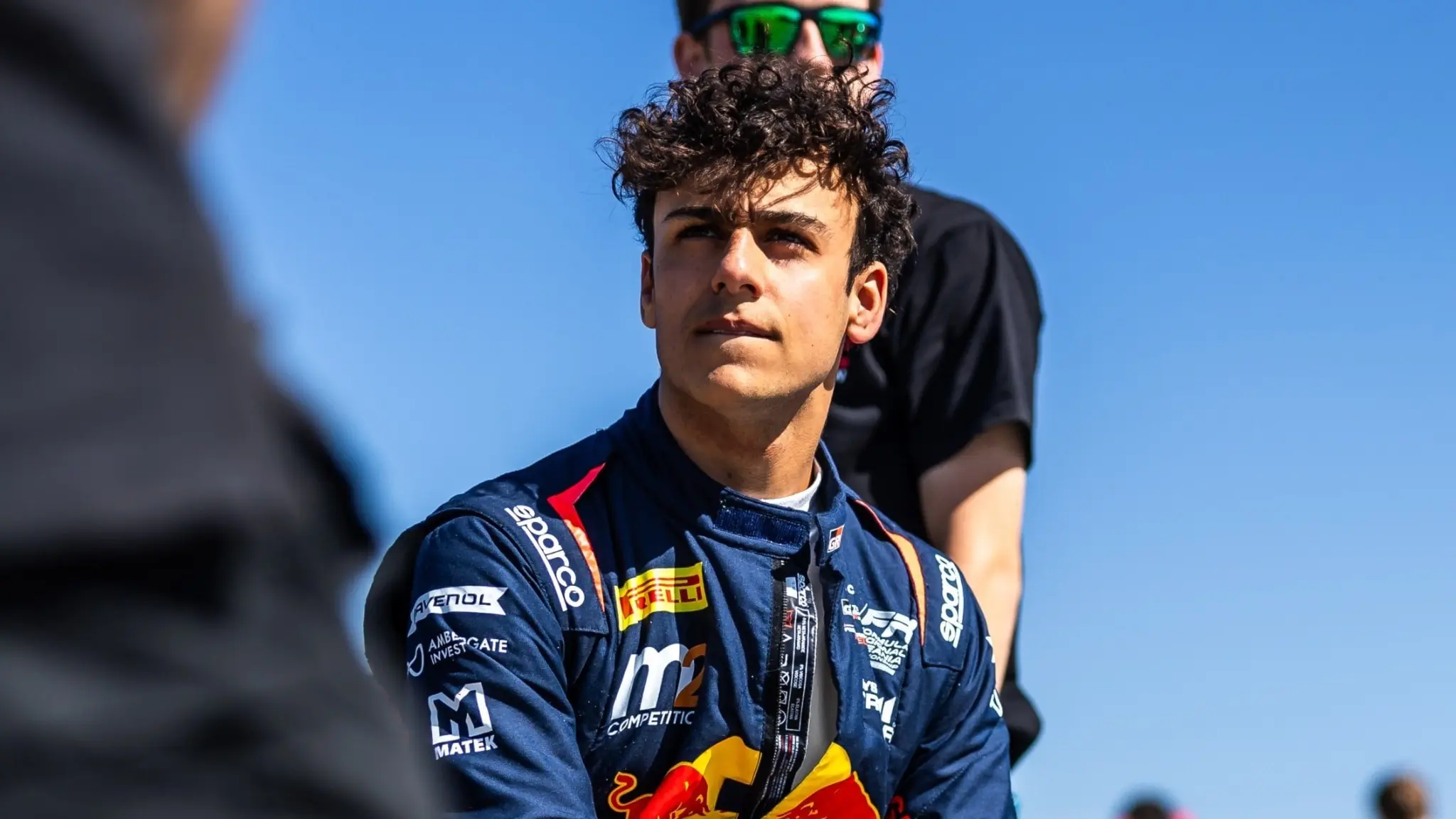 Halvsvensken Arvid Lindblad iklädd racedräkt, sittandes på sin bil under en solig dag.