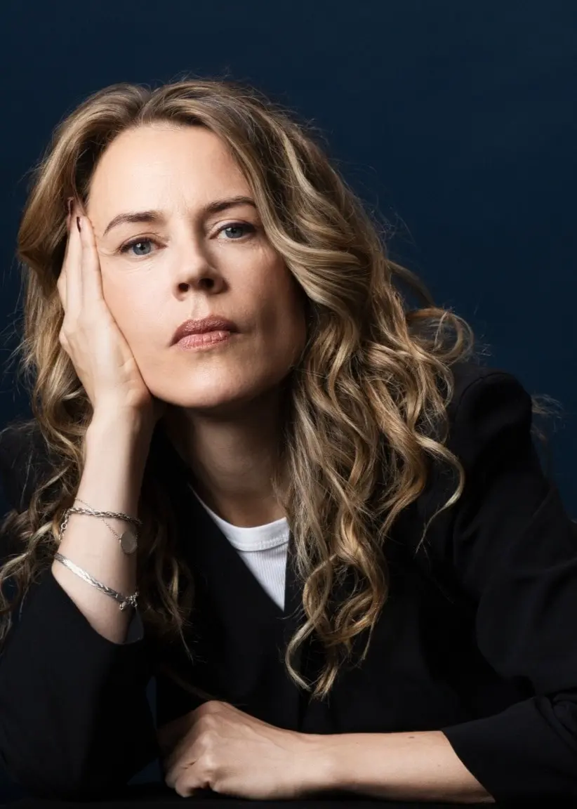 Porträttbild på låtskrivaren och författaren Annika Norlin som tittar in i kameran och låtar huvudet i höger hand.