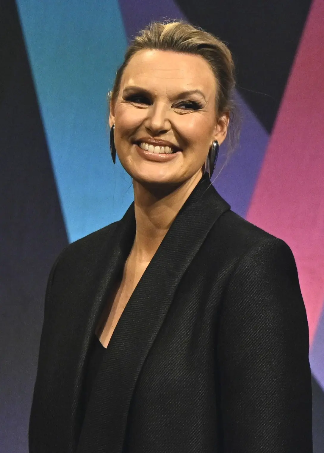 Kvinna i mörk kavaj och kvinna i grön jacka i en studiomiljö.