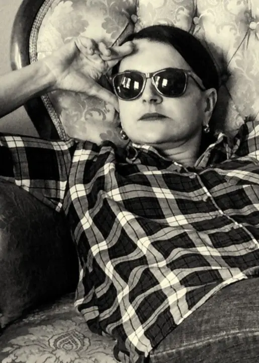 Mia halvligger i två fotöljer. Har solglasögon.