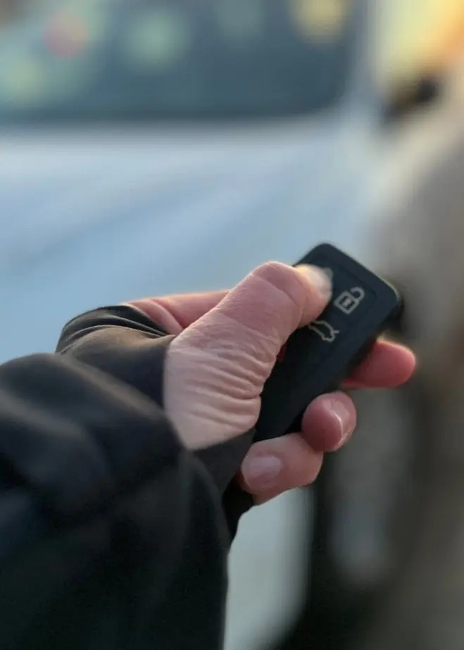 Kommunpolis Henrik Blusi i Sundsvall ger säkerhetstips om bilstöld, med bild på en hand som låser en bil med fjärrkontroll i en parkeringsmiljö.