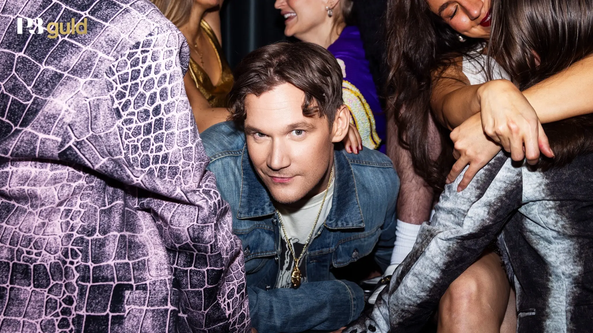 Programledare Christopher Garplind är centrerad i bild och omringad av glada människor i festmiljö.