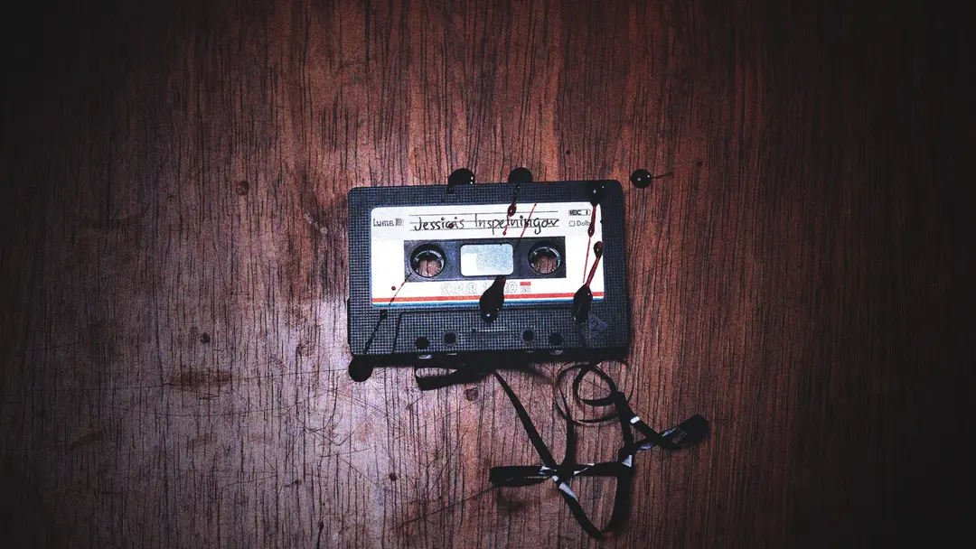 Ett utdraget, blodbestänkt kassettband märkt ”Jessicas inspelningar” på ett repigt bord.