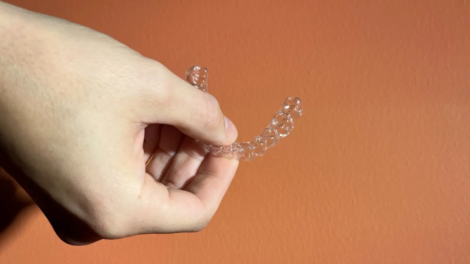 Bild på en hand som håller i en osynlig tandställning.