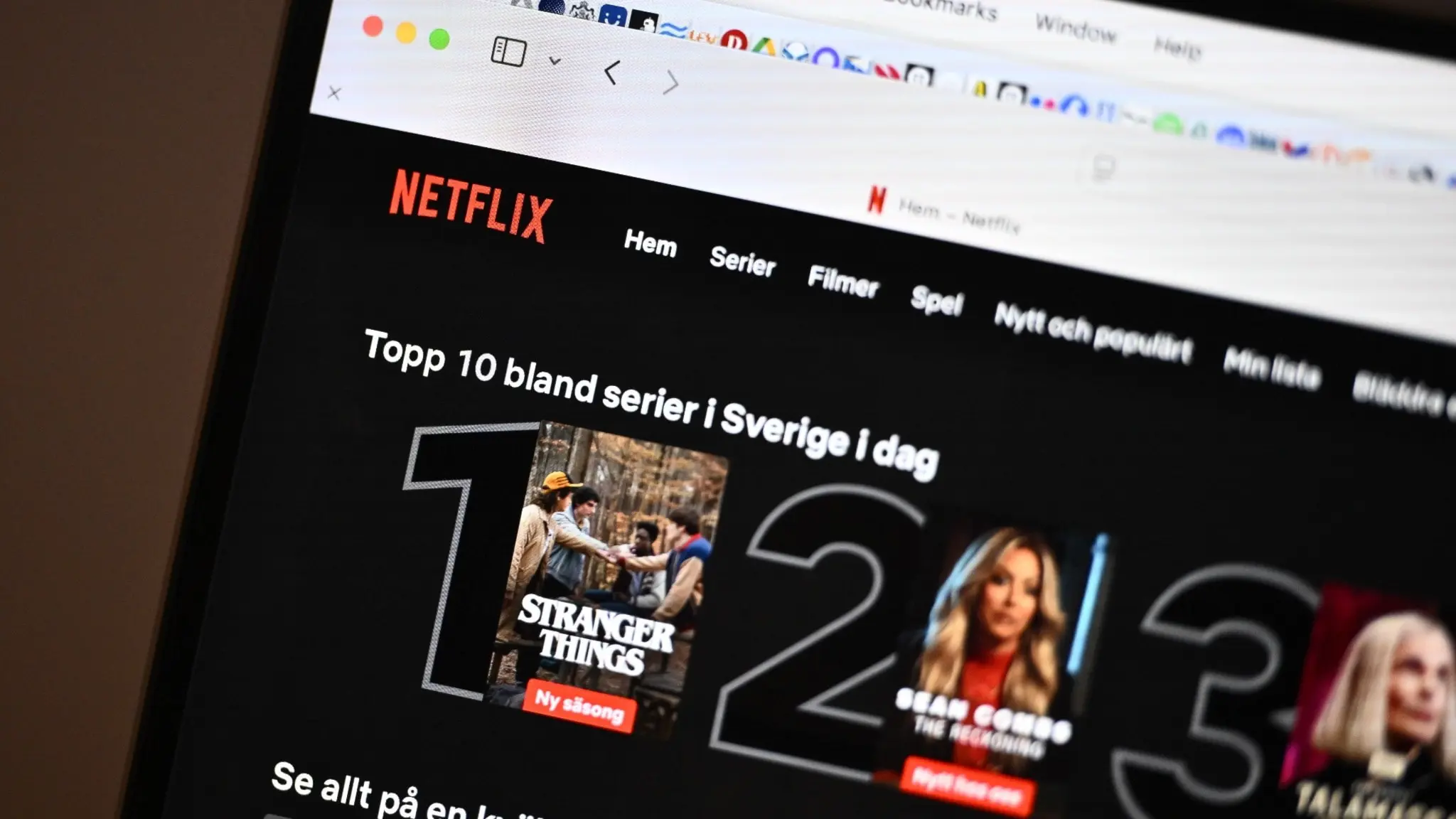 En dator visar Netflix hemsida med en lista över de topp 10 mest sedda serierna i Sverige idag. På skärmen syns omslag från populära serier och filmer.