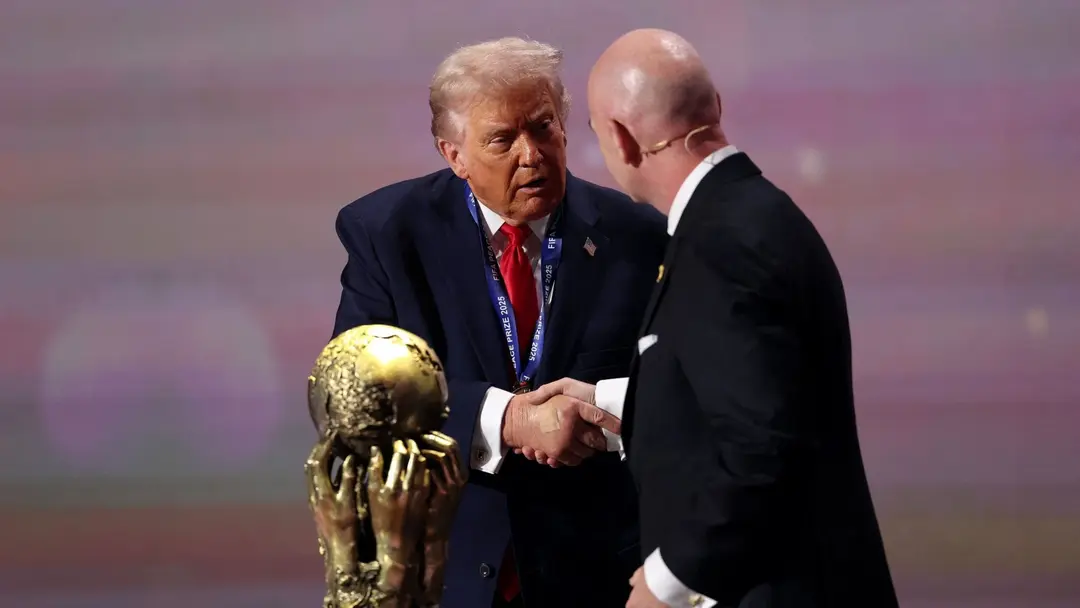 FIFA:s president Gianni Infantino skakar hand med en person framför en gyllene världscupstrofé under FIFA:s officiella lottning för VM 2026 i Washington, DC.