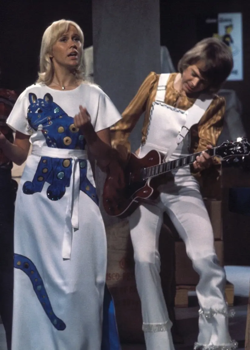 Abba står på scen. Björn håller   och spelar på sin gitarr medans Benny sitter bakom ett piano. Till vänster om herrarna står Anni-Frid och Agnetha i långa klänningar och verkar dansa.