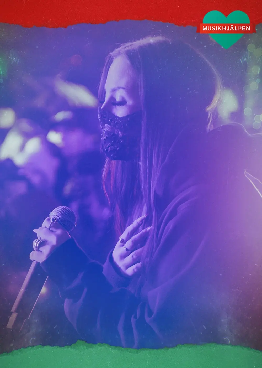 Felicia sitter på en stol och sjunger i mikrofon, hon har en svart mask över munnen.