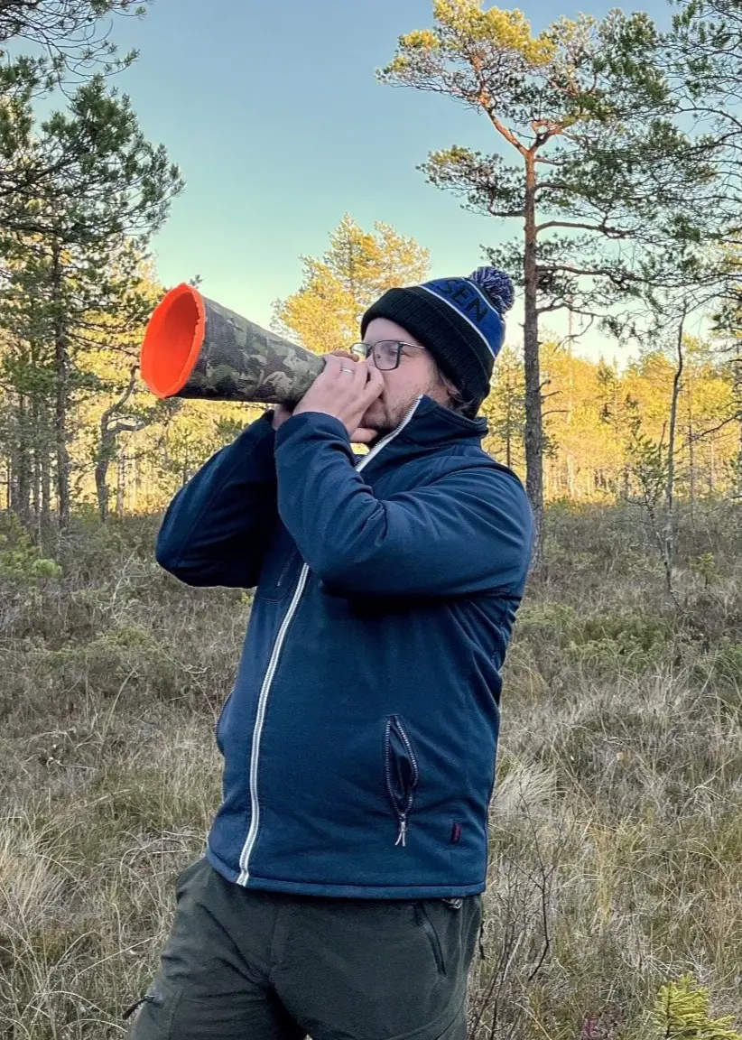 En man står i en skog med älglock i händerna.