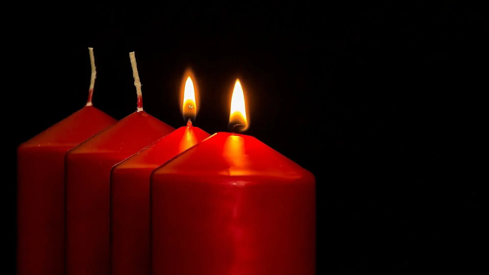 Två tända ljus i en adventsljusstake.