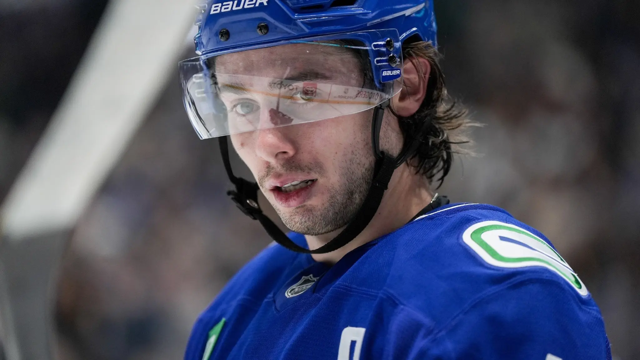 Vancouver Canucks-spelaren Quinn Hughes i blå matchtröja och hjälm väntar på en tekning under en NHL-match mot Colorado Avalanche i Vancouver.