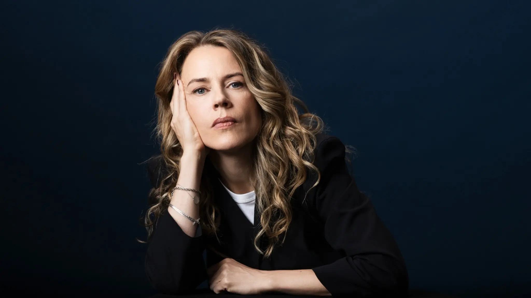 Porträttbild på låtskrivaren och författaren Annika Norlin som tittar in i kameran och låtar huvudet i höger hand.