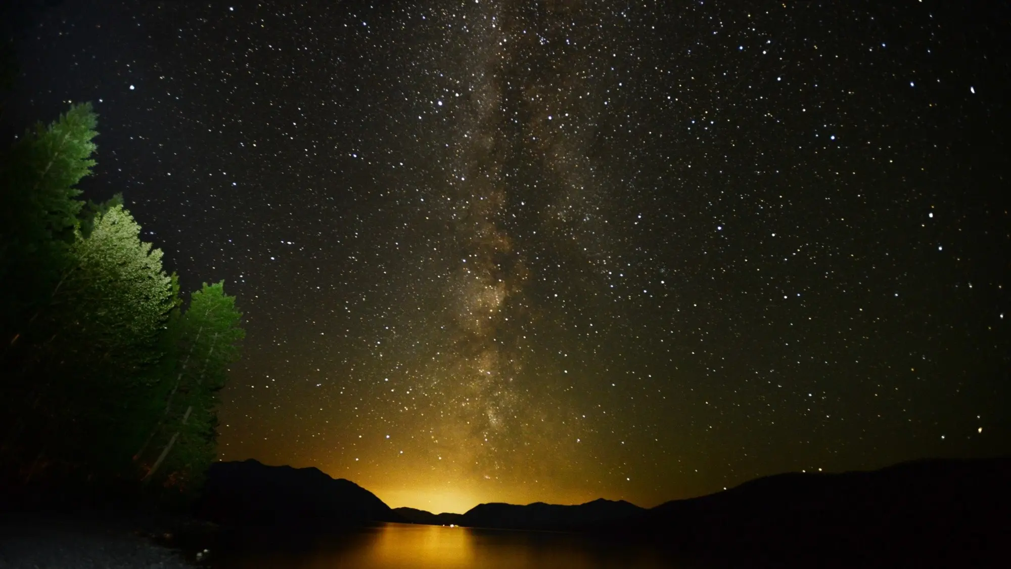 Stjärnhimmel över ett sund, precis över vattnet knallgult