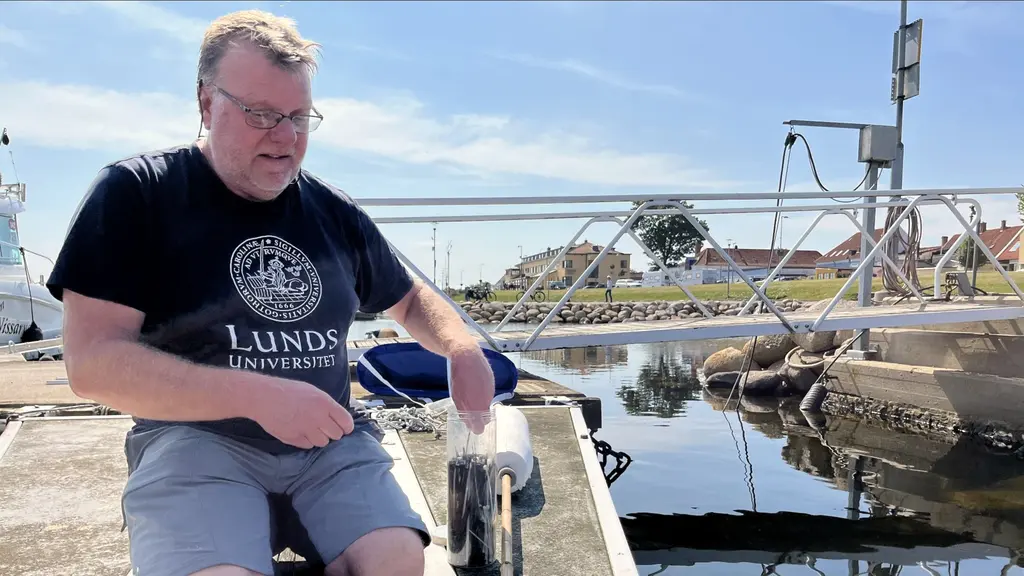 Per Carlsson, lektor i marina ekosystem, arbetar med att montera GPS-utrustning på en brygga vid en småbåtshamn med mätinstrument i bakgrunden.