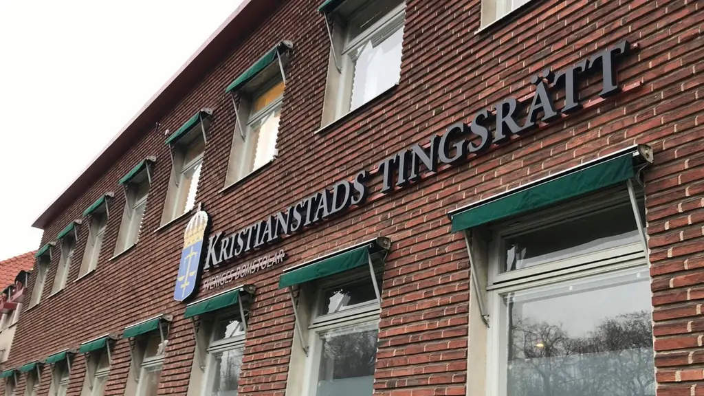 Kristianstads tingsrätts fasad i rödbrunt tegel med skylt där namnet och emblem syns tydligt. Byggnaden har flera fönster med gröna markiser och är en del av rättsväsendet i Sverige.