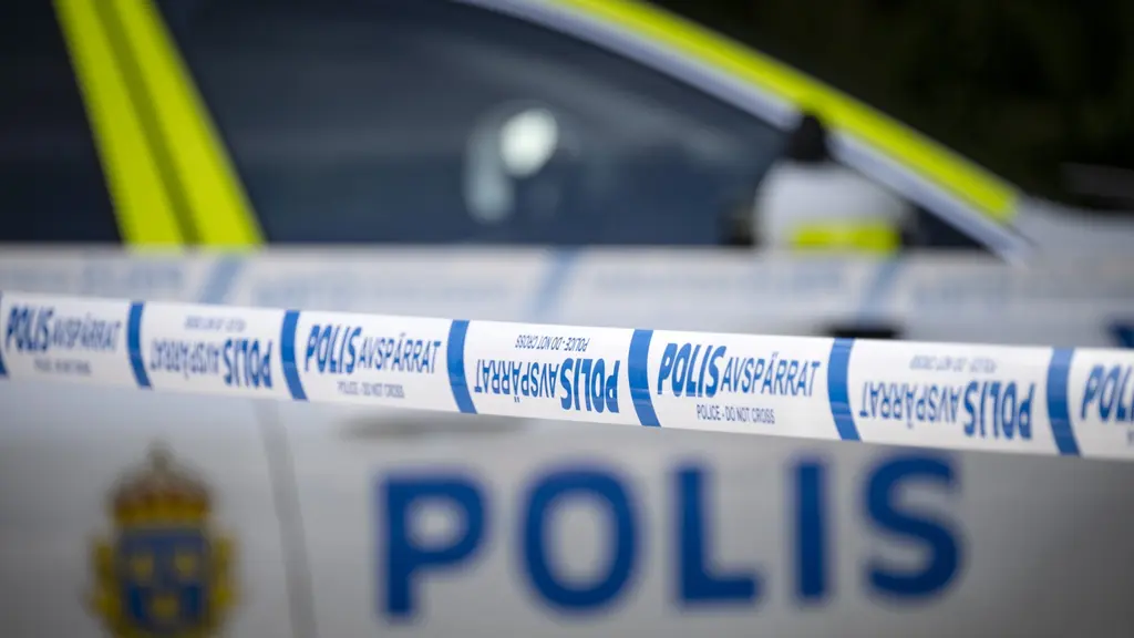 Polisbil bakom avspärrningsband.